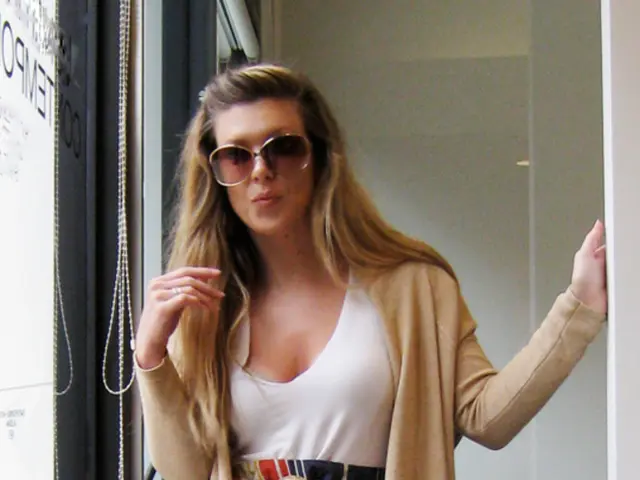 The women holding black hand bag in her right hand is standing.