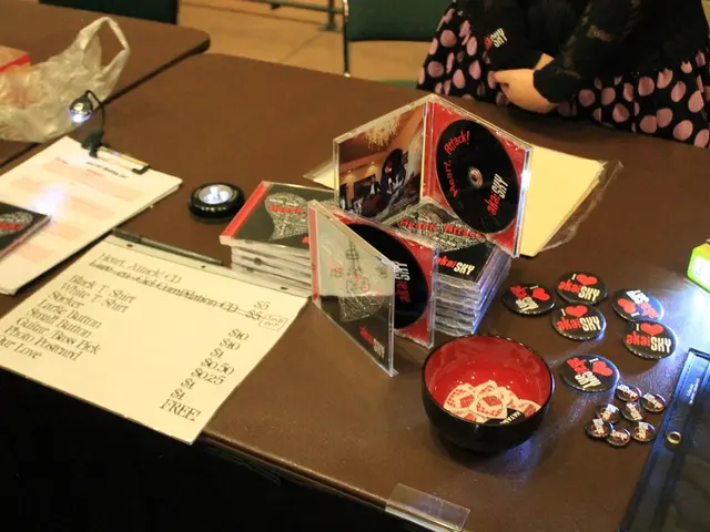 There is a table in which there are CD cases in bundle and badges and a cup with coupons in it. And...